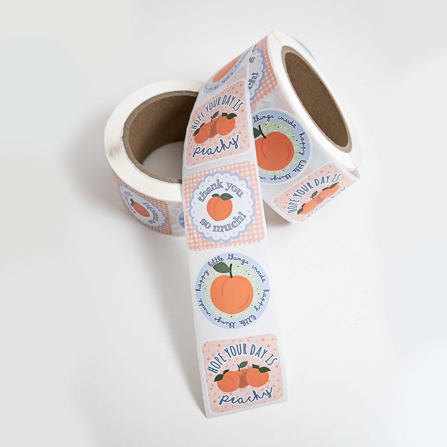 a roll of 500 customer thank you for supporting my small business stickers with a peach theme design. Stickers contain messages that say "thank you so much", "hAPPY LITTLE THINGS INSIDE", and "hope your day is peachy".   The customer thank you stickers are soft peach, blues, and green colors with a cute cottage feel with plaids and polka dots.