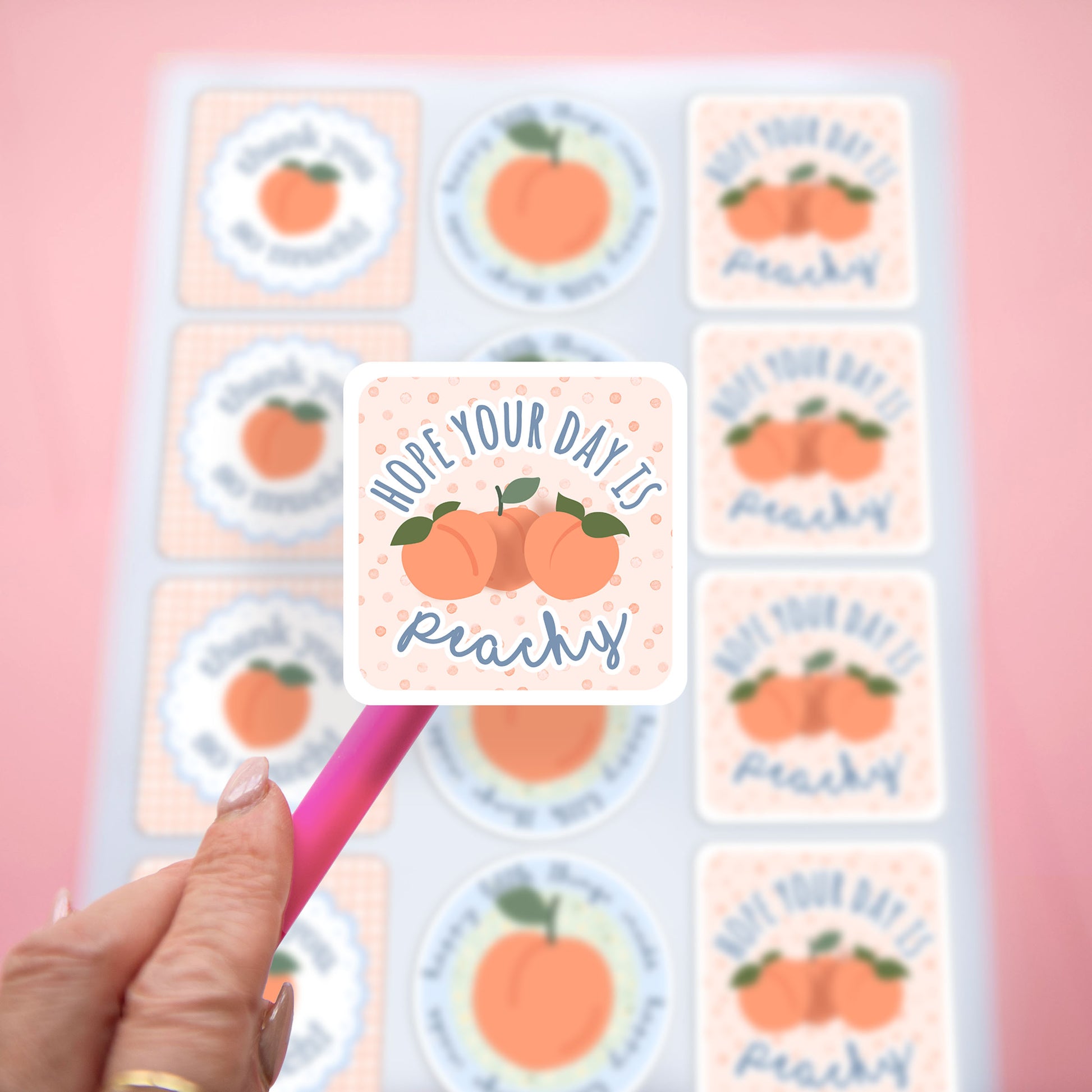 a close up of a thank you sticker with a customer thank you message that says hope your day is peachy with a full set of packaging stickers blurred in the background.
